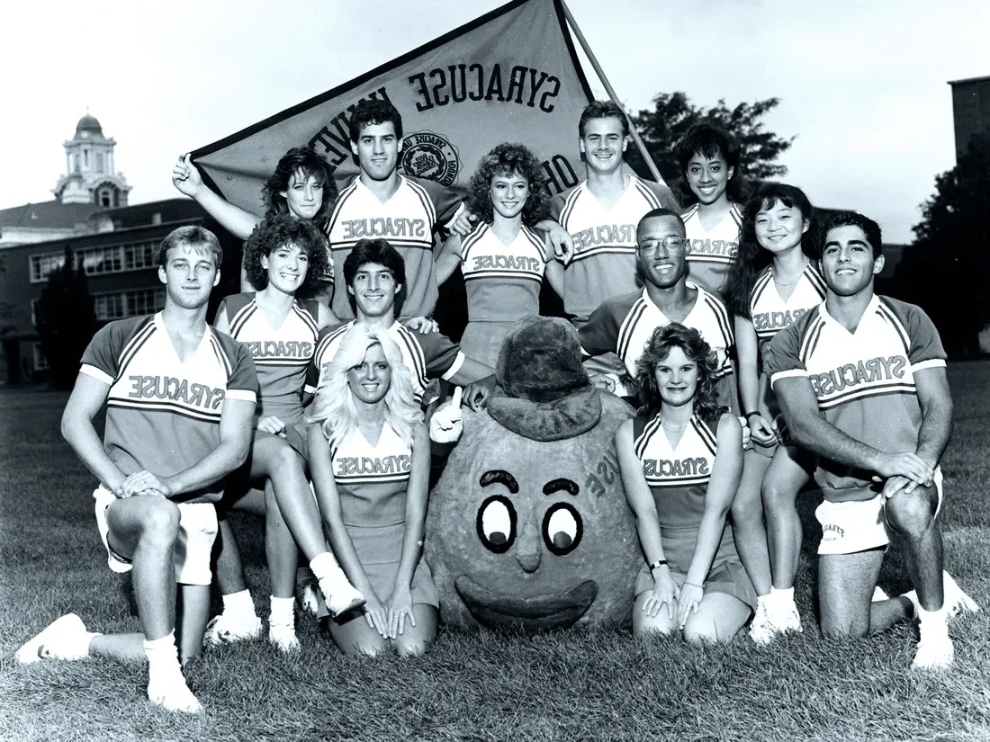 Vintage Otto the orange mascot standing outside with cheerleaders.