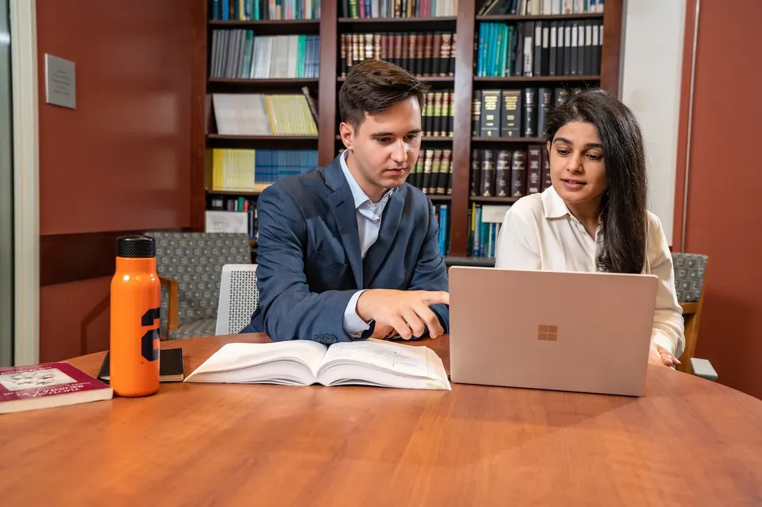 Management student and professor work together on a laptop