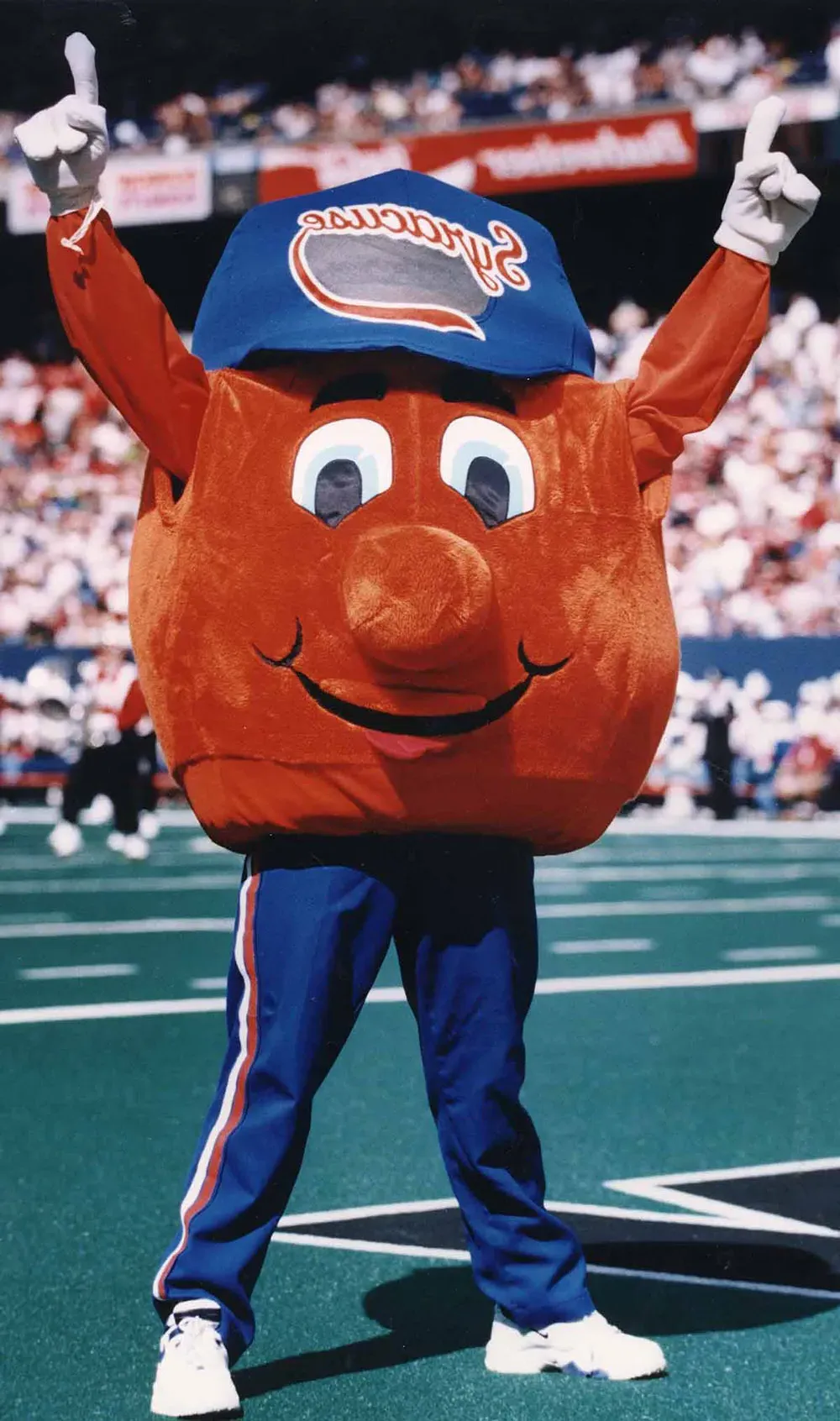 Vintage Otto the orange mascot cheering inside of stadium.
