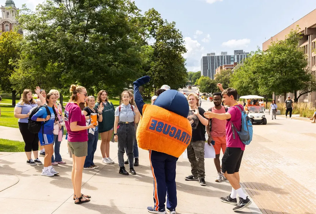 Otto and students interact on campus on a sunny summer day.