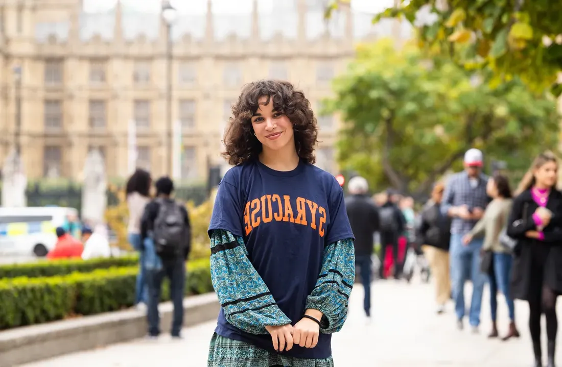 Student in London standing and smiling.