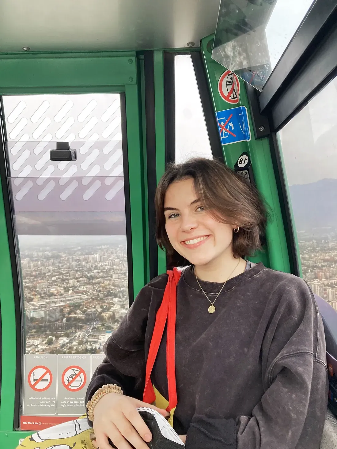 Sophie Clinton poses for a photo inside of a cable car that is in motion up a mountain.