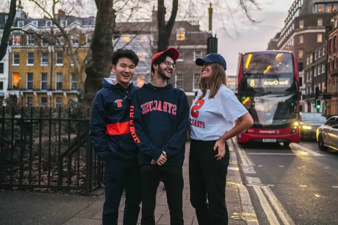 Three students on a London street smiling and laughing.